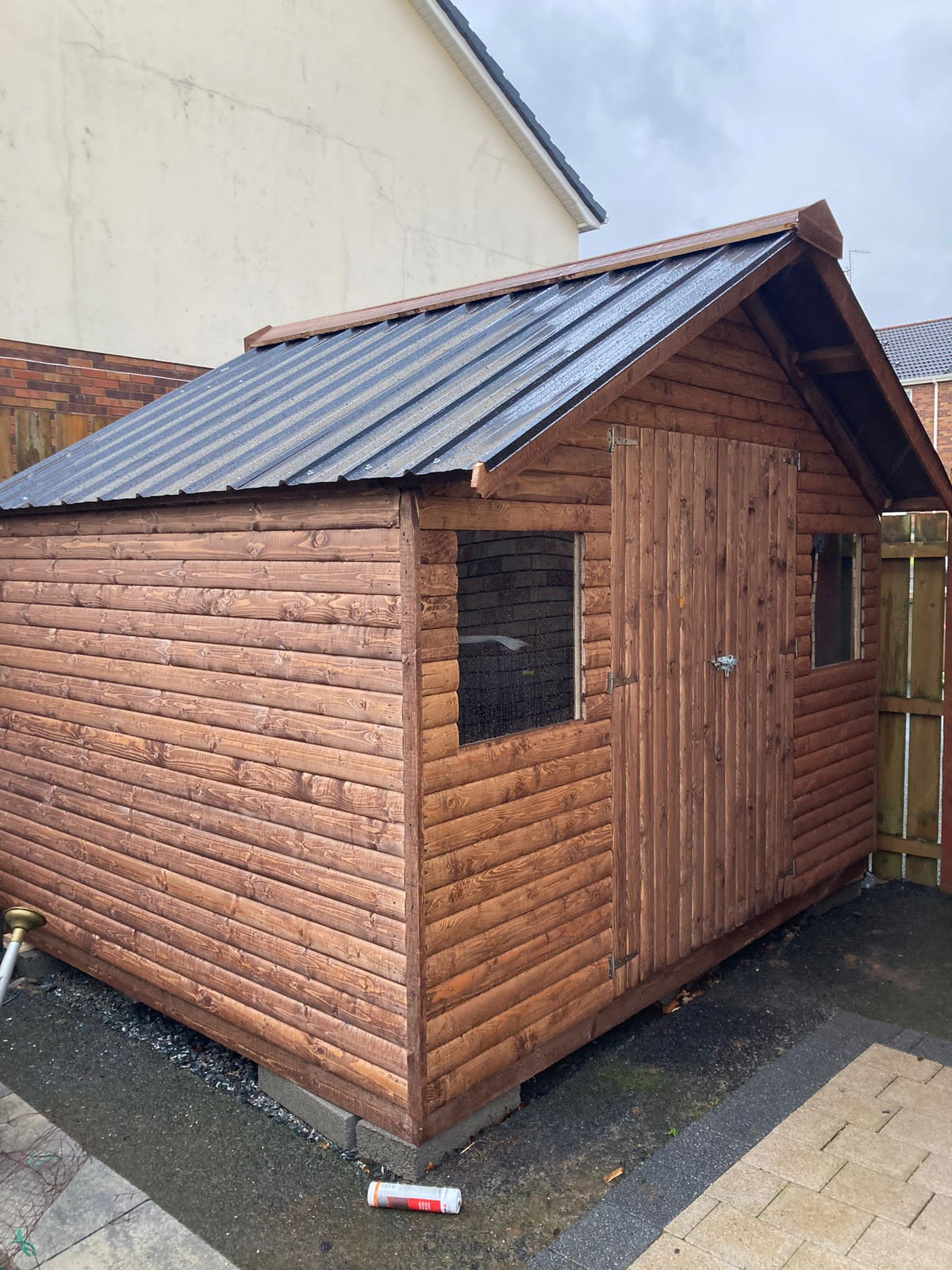 Log Cabin with 2 square windows, double doors and a tin roof.